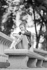 Black and white photo of a ballerina girl in jeans and pointe shoes, dancing and posing in the city on the street © Tatiana