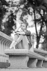 Black and white photo of a ballerina girl in jeans and pointe shoes, dancing and posing in the city on the street © Tatiana