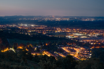 Dusk or night time landscape over small british town Malvern, showing street lamps, and denser populations in the distance.