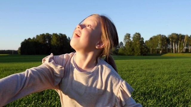 Happy child playing with a toy plane in nature during summer sunset. Girl is walking with a plane in his hands. Girl holds airplane in his hand and dreams of being a pilot. Slow motion.
