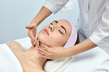 Fototapeta na wymiar young beautiful woman receiving facial massage at spa salon