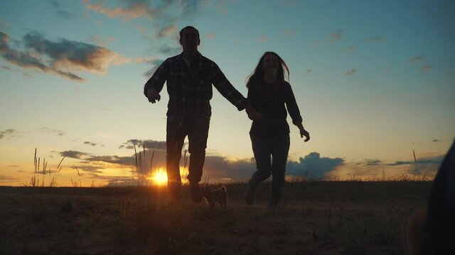 happy family couple and dog runs hands at sunset on a hilltop. concept of team business concept travel freedom victory happiness teamwork. happy family lifestyle parents hold hands run in the rays of