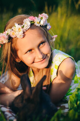 beautiful blonde girl lying on the grass with rabbits. rabbits and cabbage. little girl in a light green dress and with a wreath on her head. to celebrate Easter