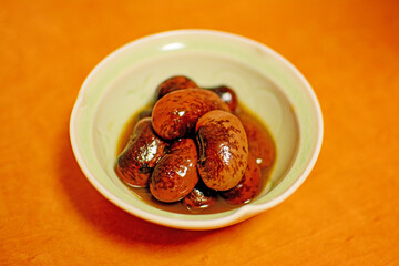 白い陶器の器に盛り付けられた丸々と膨らんだ信州名産のインゲンマメ属の大きな紫花豆の煮物。The cooked dish of some scarlet runner beans 旅行、旅先、シルバーウィーク、紅葉。