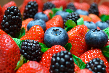 Close-up of a berry set of blueberries, strawberries, blackberries and fresh mint in bright colors and blurred background