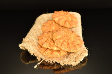 Fragrant tasty, sweet cereal cookies on a jute napkin, close-up, on a black background.