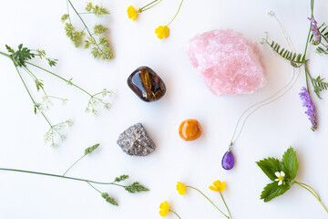 Semiprecious gemstones or crystals on white background with wild summer flowers