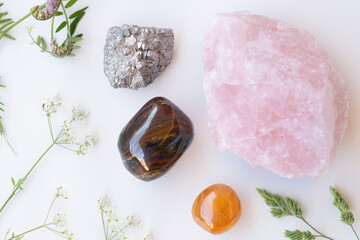 Semiprecious gemstones or crystals on white background with wild summer flowers