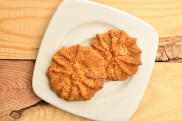 Fragrant tasty, sweet cereal cookies on a white ceramic saucer, close-up, on a wooden table.