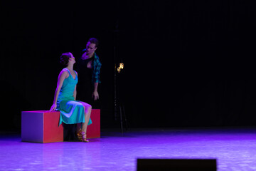 A pair of dancers a man and a woman perform in a theater on stage in a dance musical show.