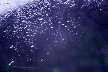 Fototapeta na wymiar drops of pod on frosted glass on a dark background