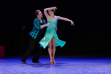 A pair of dancers a man and a woman perform in a theater on stage in a dance musical show.