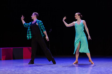 A pair of dancers a man and a woman perform in a theater on stage in a dance musical show.