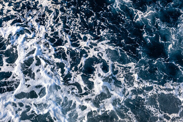 Top down aerial view of sea water surface. White foam waves texture as natural background.