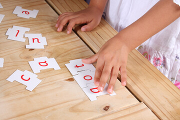 A child's hands moving letters to make a word