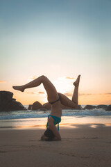 Fototapeta na wymiar Young attractive latin woman wearing a bikini practicing yoga on the beach at sunset, healthy mental and body lifestyle concept.