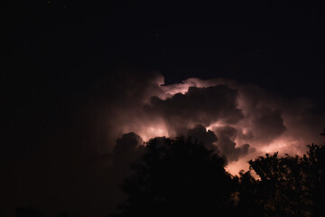 Lightning Striking Behind Clouds in Night Sky
