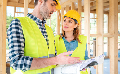 Team engineer and architect are meeting to plan for new project of wood frame house on building site
