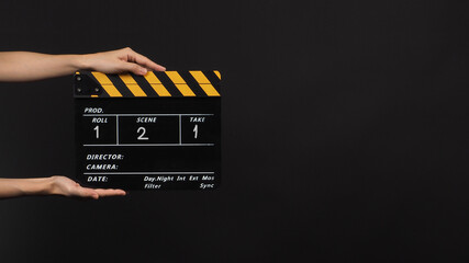 Hand is holding Black with yellow color clap board or movie slate  with number on black background.