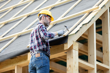 Roofer builder working on roof structure at construction site