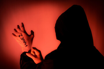 mysterious dark man with hoodie wearing latex gloves, preparing for second wave of coronavirus