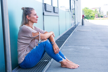 blond woman in her 40s sitting outdoors looking pensive