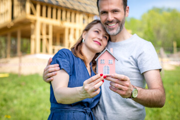 Loving couple building their own home with house under construction in background