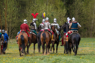 A knight in vintage armor of the 15th century rides a horse across a field for a tournament