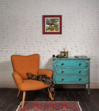 Bright orange retro armchair with plaid against white brick wall with shabby chic vintage turquoise cabinet in living room and hanged painting, with clipping path for the painting