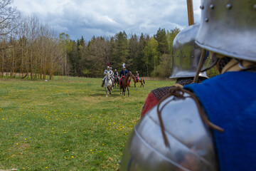 A knight in vintage armor of the 15th century rides a horse across a field for a tournament