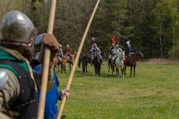 A knight in vintage armor of the 15th century rides a horse across a field for a tournament