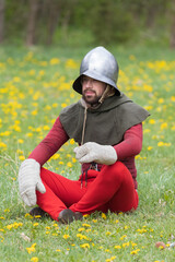 A knight in vintage armor of the 15th century rides a horse across a field for a tournament