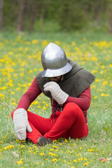 A knight in vintage armor of the 15th century rides a horse across a field for a tournament