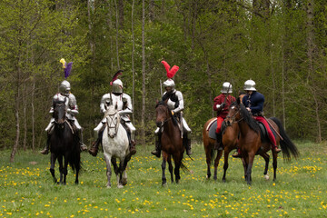 A knight in vintage armor of the 15th century rides a horse across a field for a tournament