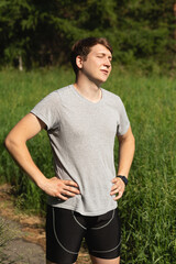 Fototapeta premium A man is resting after a long run in the park in nature. Cardio exercise on the street. Healthy lifestyle concept.