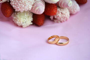 Close-up of wedding rings on background a bouquet with strawberries in chocolate/Wedding Rings/Wedding Rings