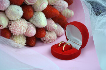 Close-up of wedding rings in a red box on background a bouquet with strawberries in chocolate/Wedding Rings/Wedding Rings