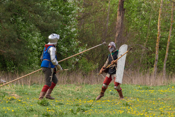 Knights in armor fight on the battlefield. Reconstruction of an ancient tournament of the 15th...