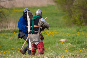 Knights in armor fight on the battlefield. Reconstruction of an ancient battle of the 15th century.