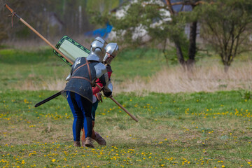 Knights in armor fight on the battlefield. Reconstruction of an ancient tournament of the 15th...