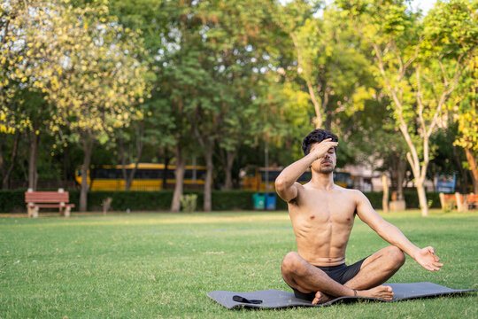 A young indian shredded teenage boy doing yoga aasan in the park on international yoga day, anulom vilom aasan.