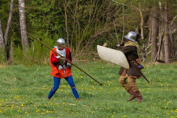 Knights in armor fight on the battlefield. Reconstruction of an ancient tournament of the 15th...