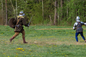 Knights in armor fight on the battlefield. Reconstruction of an ancient tournament of the 15th...