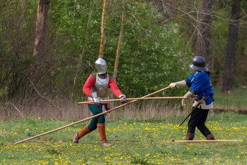 Knights in armor fight on the battlefield. Reconstruction of an ancient tournament of the 15th...