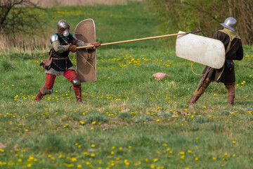 Knights in armor fight on the battlefield. Reconstruction of an ancient tournament of the 15th...