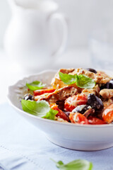 Penne pasta baked with pork tenderloin, cherry tomatoes, black olives and cheese. Close up