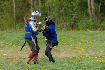 Knights in armor fight on the battlefield. Reconstruction of an ancient tournament of the 15th...