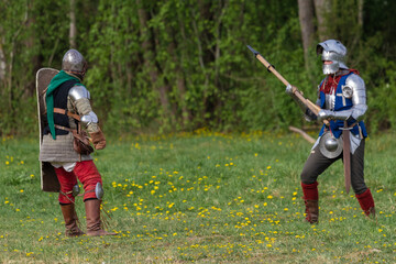 Knights in armor fight on the battlefield. Reconstruction of an ancient tournament of the 15th...