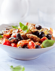 Penne pasta baked with pork tenderloin, cherry tomatoes, black olives and cheese. Close up.
