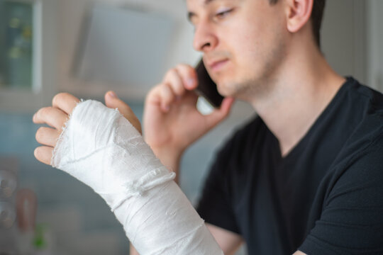 The person with a broken hand speaks on the phone. Working as a freelancer during a sick leave